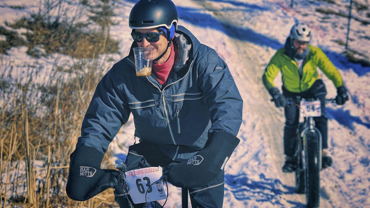 A fat bike rider holds his beer in his teeth after a fast descent during the Fat Cupid Classic.
